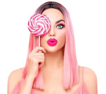 A woman with pink hair holding a lollipop.